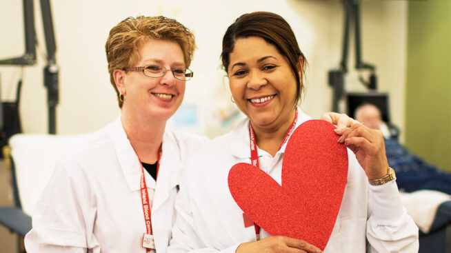 Two RIBC staff members smiling with a heart in one member's hands.